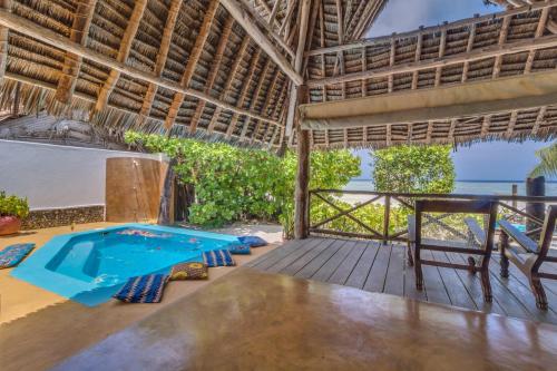 an outdoor deck with a swimming pool and a table at SeVi Boutique Hotel in Matemwe