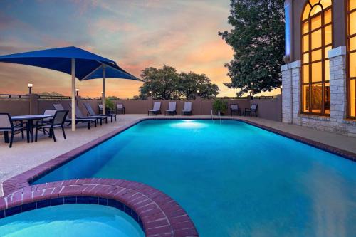 a swimming pool with a table and an umbrella at Holiday Inn Express & Suites Cedar Park (Nw Austin) by IHG in Cedar Park