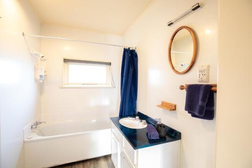 a bathroom with a sink and a tub and a mirror at Alpine View Motel in Te Anau