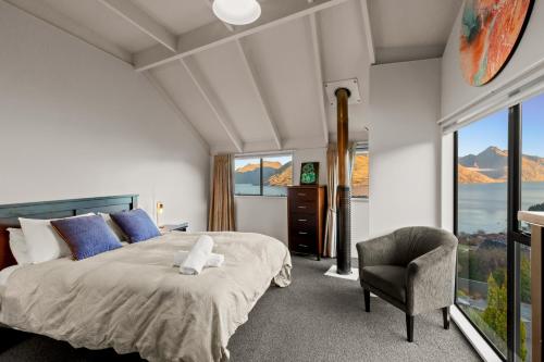 une chambre avec un lit, une chaise et des fenêtres dans l'établissement The Hill Haven Queenstown, à Queenstown