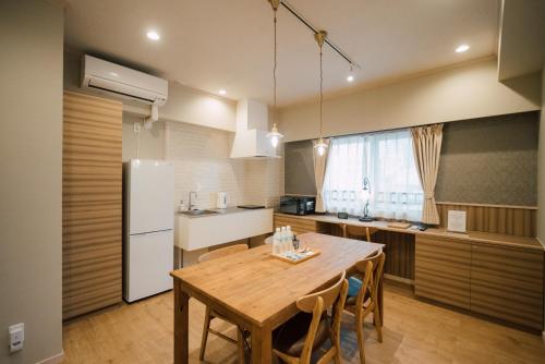 a kitchen with a wooden table and a white refrigerator at ホテル天使館 久茂地 -Tenshi-Kan- in Naha