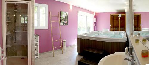 baño con paredes de color púrpura, bañera y lavamanos en Au Coeur du Bien-Etre, gîte avec piscine chauffée et couverte, SPA, sauna, massages, en Monteaux