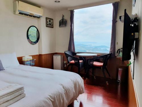 una camera da letto con un letto, un tavolo e una finestra di Kao Mama B&B a Jiufen