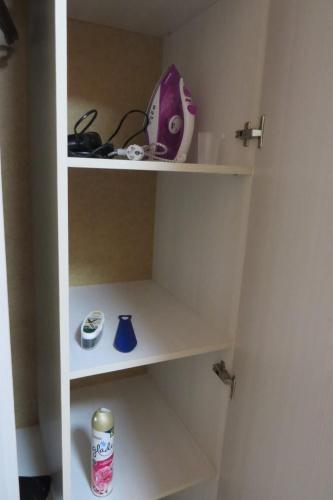 une étagère blanche avec un article violet sur elle dans l'établissement 1 комнатная квартира в Щучинске, à Chtchoutchinsk