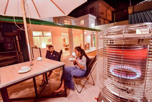 a man and woman sitting at a table next to a fan at Top Terrace Cottage in Nuwara Eliya
