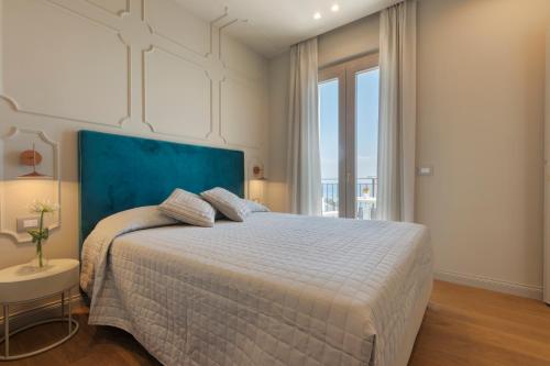 a bedroom with a large bed with a blue headboard at Diecidodici BoutiqueRooms in Sirolo