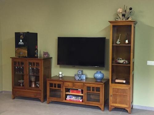 a living room with a flat screen tv and two wooden entertainment centers at Casa Almoravid in Daroca de Rioja
