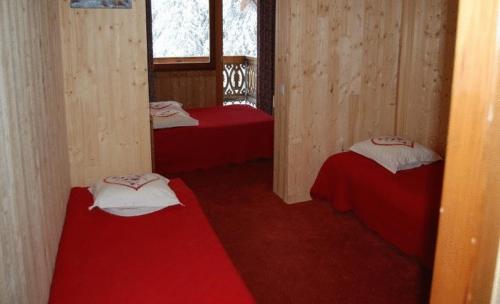 2 camas rojas en una habitación con ventana en Hôtel De La Couronne, en Mijoux