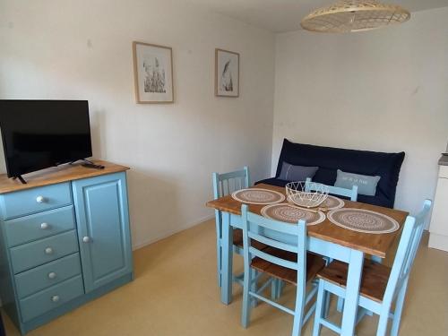 ein Esszimmer mit einem Tisch mit Stühlen und einem TV in der Unterkunft Logement 106 2-4 Personnes 500 m plage classé 2 Etoiles in Dolus d'Oléron