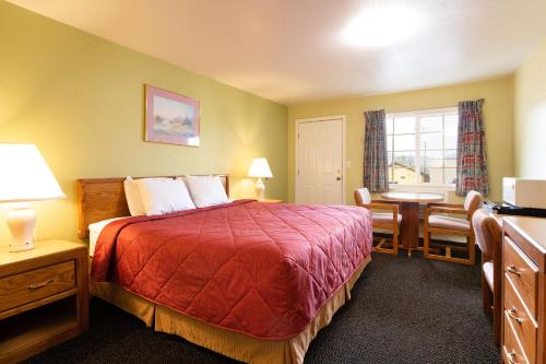 a hotel room with a bed and a desk and a window at Roseburg Inn in Roseburg