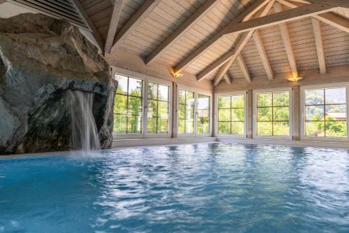 a swimming pool with a waterfall in a room with a rock wall at Bergrose Hideaway in Strobl