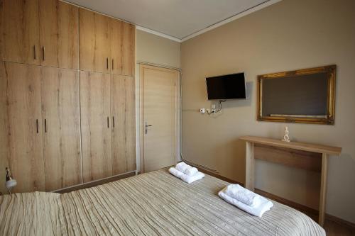 - une chambre avec un lit et une télévision murale dans l'établissement C.L.A. City Loux Apartment, à Alexandroúpolis
