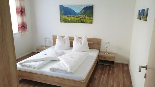 Schlafzimmer mit einem Bett mit weißer Bettwäsche und Kissen in der Unterkunft Stockers Apart in Umhausen
