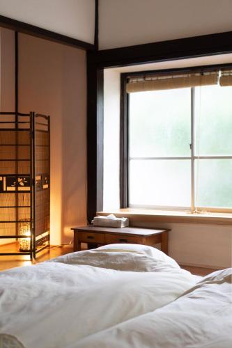 a bedroom with a white bed and a window at おとまち 甘藍 Otomachi Kanran in Kure