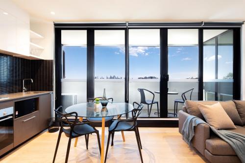 uma cozinha e sala de estar com uma mesa de vidro e cadeiras em Artel Apartments Brunswick em Melbourne