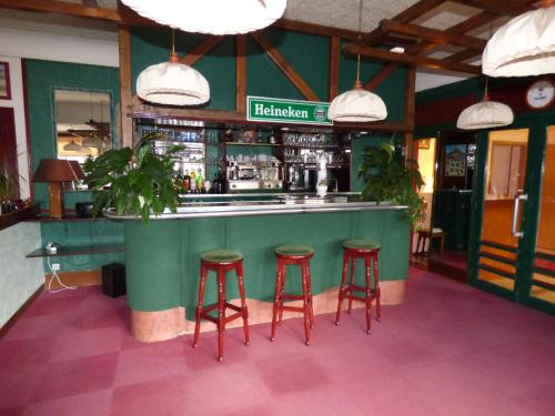 eine Bar in einem Restaurant mit drei Stühlen in der Unterkunft Hôtel La Pocatière in Coutances