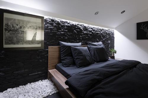 - une chambre avec un lit et un mur en briques noires dans l'établissement The Attic, à Zagreb