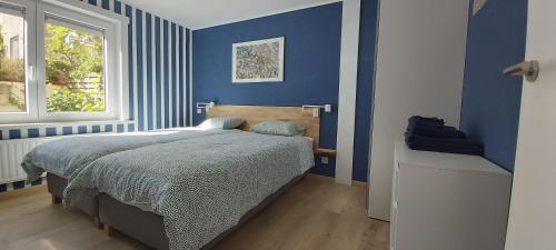 Dormitorio azul con cama y ventana en Seagarden by Valdemosa, en De Haan