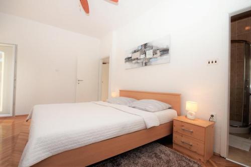 a white bedroom with a bed and a night stand at Apartment Deni in Pula