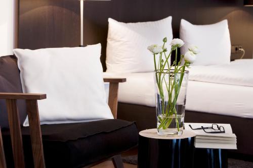 Hotel zum Rössel في كاندل: مزهرية من الزهور على طاولة بجوار سرير