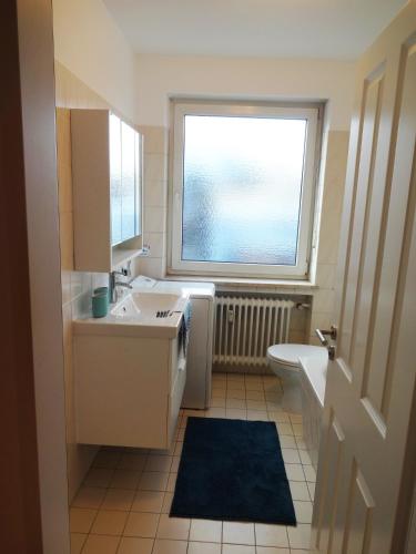 a bathroom with a sink and a toilet and a window at Moderne Wohnungen am Bahnhof Dachau mit direkter S-Bahn Verbindung nach München in Dachau