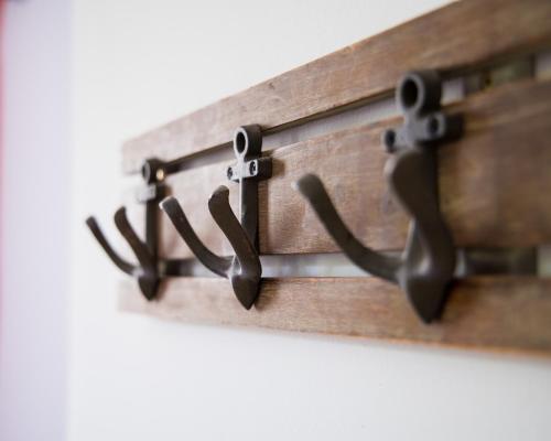 a wooden coat rack with three metal hooks at Sobe Argo Izola in Izola