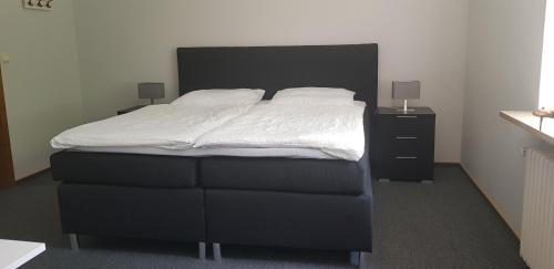 a bedroom with a bed with white sheets and two night stands at Hotel Haus Hubertus in Schneverdingen