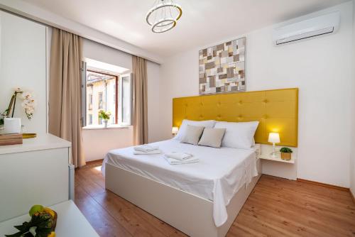 um quarto com uma grande cama branca e uma cabeceira amarela em Luxury rooms Zadar old town em Zadar