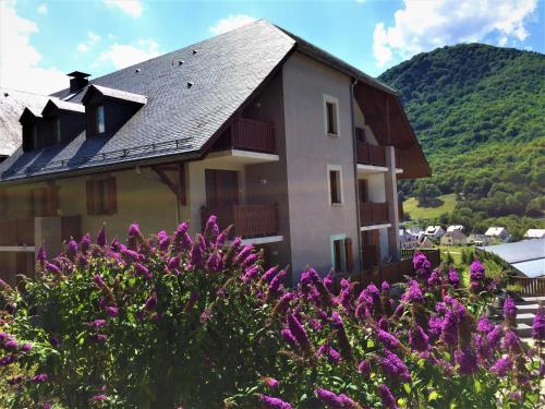 una casa con flores púrpuras delante de ella en Résidence Balcons de La Neste, en Arreau