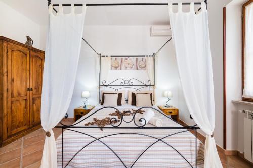 a bedroom with a canopy bed with white curtains at Oasi Caprolace in Sabaudia