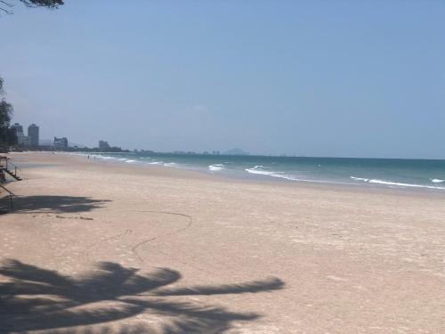 a beach with a shadow of a palm tree on it at Sea you pool villa Hua Hin in Hua Hin