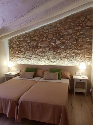 a bedroom with two beds and a stone wall at Cal Moreno in Pratdip