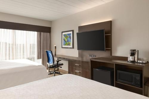 a hotel room with a bed and a desk with a television at Holiday Inn Express Hotel & Suites Fort Myers East - The Forum by IHG in Fort Myers