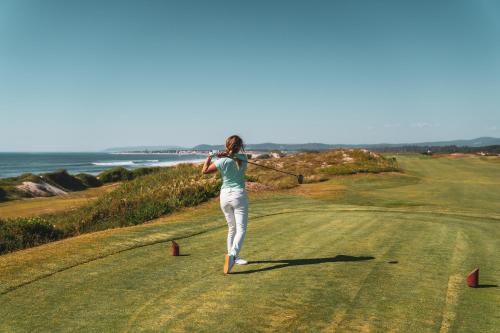 a woman swinging a club on a golf course at Sense of Ofir in Fão