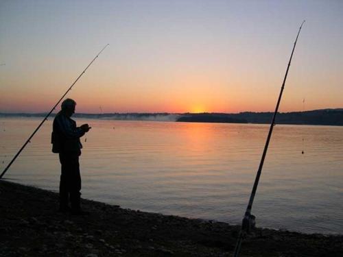a man standing on the beach with two fishing rods at 3M Pansioni in Vlasina Rid