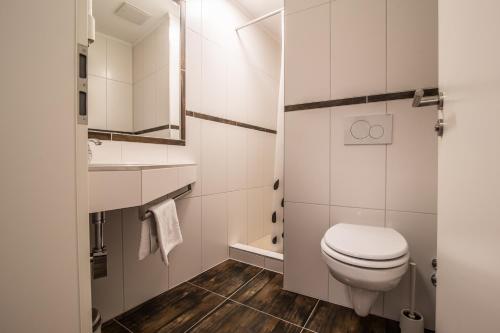 a white bathroom with a toilet and a sink at Hotel am Markt in Saarburg