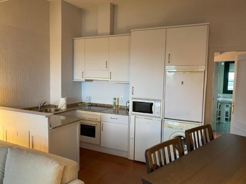 a kitchen with white cabinets and a table with chairs at Ático en Tapia de Casariego con vistas a la playa. in Tapia de Casariego