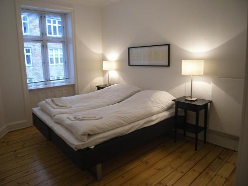 a bed in a room with two lamps and a window at Ydunsgade in Copenhagen