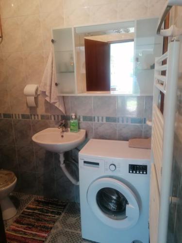 a bathroom with a washing machine and a sink at Apartman Juka in Krasno Polje