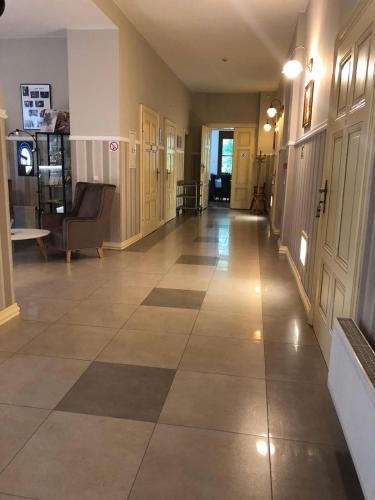 a hallway with a large tile floor in a building at Park Hotel Dobrodzień in Dobrodzień