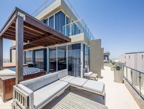 una casa con un balcón con muchas ventanas en Infinity Self Catering Apartments en Bloubergstrand