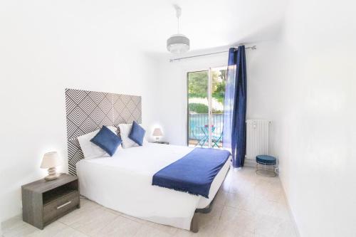ein weißes Schlafzimmer mit einem großen Bett und einem Fenster in der Unterkunft Les Mimosas in Roquebrune-Cap-Martin
