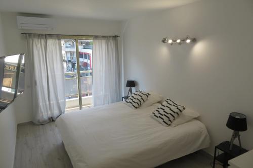 una camera da letto con un letto bianco con due cuscini sopra di Luxe 6 couchages proxi bord de mer centre ville a Cannes