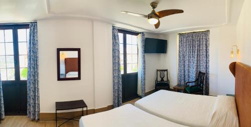 a bedroom with two beds and two windows at Hotel Don Miguel in Ronda