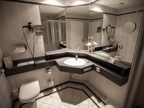 ein Bad mit einem Waschbecken und einem WC in der Unterkunft Hotel "Schloss Friedestrom" in Dormagen