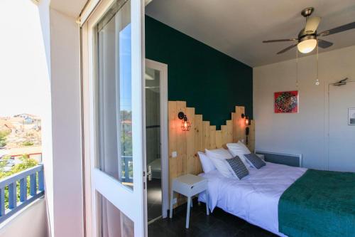 a bedroom with a bed with a green accent wall at Hôtel La Baïne in Capbreton