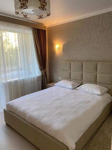 a bedroom with a large white bed with a window at 2-ухкомнатная современная новая квартира в центре города in Kostanay