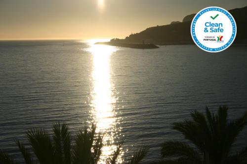 a view of the ocean with the sun setting over the water at Apartamento Mar II WITH PARKINg in Sesimbra