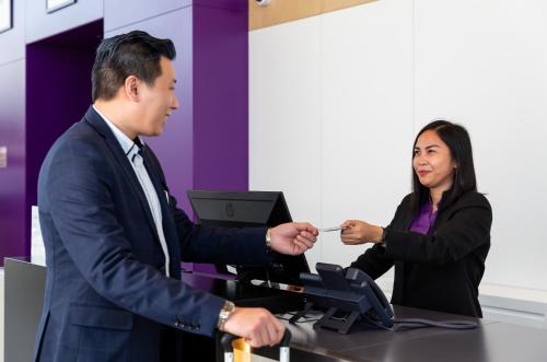 a man in a suit handing a woman a card at Premier Inn Dubai Dragon Mart in Dubai