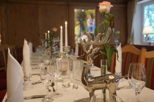 a table with wine glasses and a deer statue on it at Gartenhotel Kloepferkeller in Eibiswald